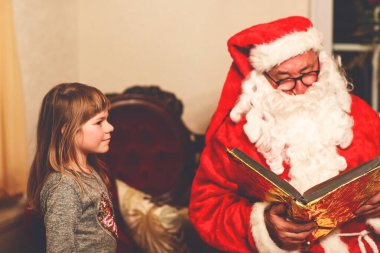 Nikolaus veya Weihnachtsmann adında Almanca Noel Baba 'yla konuşan küçük bir kız. Mutlu gülümseyen çocuk hediye bekliyor. Altın kitaplı Noel Baba. Xmas, çocukluk, tatil.