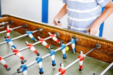 Masa futbolu oynayan çocuğun yakın çekimi. Mutlu heyecanlı çocuk aile oyunlarıyla eğleniyor kardeşleriyle ya da arkadaşlarıyla. Pozitif çocuk.