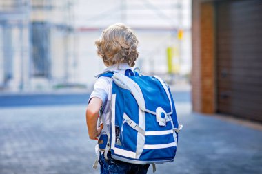 Çantası olan küçük mutlu çocuk. Okul çocuğu, okula giderken yolda. Dışarıdaki sağlıklı sevimli çocuğun portresi. Öğrenci, öğrenci, okula dönün. İlkokul çağında.