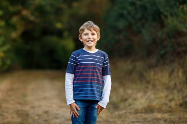 Ormandaki küçük havalı çocuğun portresi. Mutlu sağlıklı çocuk sıcak güneşli bir sonbaharda eğleniyor. Aile, doğa, aşk ve aktif eğlence.