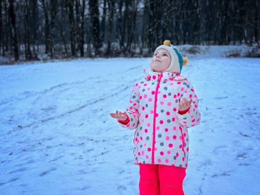 Güzel Kış Parkı 'nda Eğlenen Komik Küçük Kız. Karla oynayan mutlu okul çocuğu, kar ve kış aktiviteleriyle ilgili mutluluk.