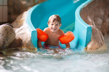 Active adorable little preschool kid boy with swimmies learning to swim in an indoor pool. Active and fit leisure for children. Happy child making sports and learning safe swimming. clipart