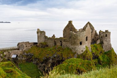 Dunluce Şatosu 'nun kalıntıları, Antrim, Kuzey İrlanda, güneşli bir günde yarı bulutlu gökyüzü. Vahşi Atlantik Yolu yakınlarındaki eski İrlanda kalesi