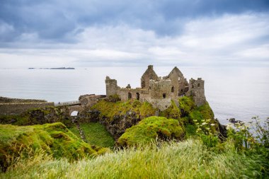 Dunluce Şatosu 'nun kalıntıları, Antrim, Kuzey İrlanda, güneşli bir günde yarı bulutlu gökyüzü. Vahşi Atlantik Yolu yakınlarındaki eski İrlanda kalesi