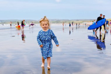 Ballybunion Sörfçü Plajı 'nda küçük tatlı bir kız, İrlanda' nın batı sahilinde oynarken eğleniyor. Mutlu çocuk İrlanda yazının ve güneşli günün tadını çıkarıyor.