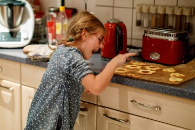 Küçük kız evde Noel kurabiyesi pişiriyor. Mutlu çocuk ve zencefilli kurabiye.