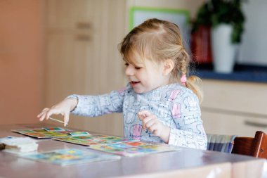 Heyecanlı, gülümseyen küçük kız iskambil oynuyor. Mutlu sağlıklı çocuk hafızasını eğitiyor, düşünüyor. Çocuk için evde yaratıcı bir eğlence ve eğitim. Evde aile aktivitesi