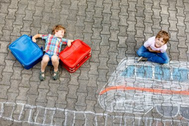 İki küçük çocuk çocuklar asfalt üzerinde renkli mangası ile tren resim çizim ile eğleniyor. Çocuk tebeşir ve pastel boya resim ile eğleniyor. Tatil ve seyahat oluyor. Arkadaş grubu bavul.