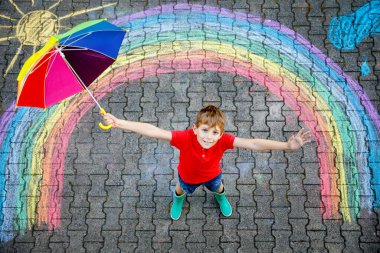 Lastik çizmeli, gökkuşağı güneşli, yağmur damlalı bulutlu renkli tebeşirle boyanmış mutlu çocuk yaz mevsiminde. Yazın dışarıda çocuklar için yaratıcı bir eğlence..
