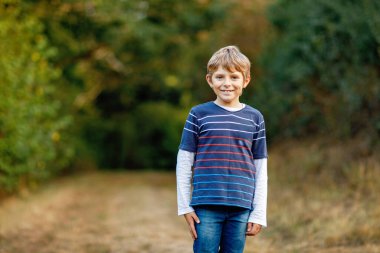 Ormandaki küçük havalı çocuğun portresi. Mutlu sağlıklı çocuk sıcak güneşli bir sonbaharda eğleniyor. Aile, doğa, aşk ve aktif eğlence.