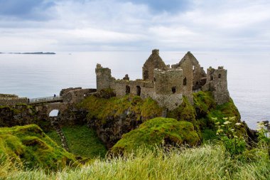 Dunluce Şatosu 'nun kalıntıları, Antrim, Kuzey İrlanda, güneşli bir günde yarı bulutlu gökyüzü. Vahşi Atlantik Yolu yakınlarındaki eski İrlanda kalesi