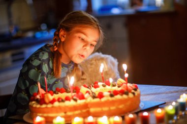 Mutlu küçük kız sekizinci doğum gününü kutluyor. Evde sekiz numara olarak ev yapımı pastayla gülümseyen sevimli bir çocuk. Mutlu sağlıklı okul çocuğu pastaya 8 mum üflüyor..