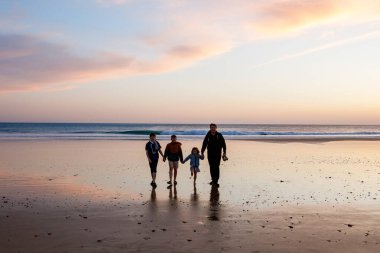 Gün batımında üç çocuk ve babanın resimli mutlu çocukları ve babaları sahilde. Mutlu bir aile, iki okul çocuğu ve küçük bir anaokulu kızı. Kardeşler birlikte eğleniyor. Bağlanma.