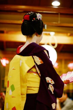 KYOTO, JAPONYA - 18 Mayıs 2015: Japon geleneksel dansını gösteren Maiko çırağı. Maiko bir çırak geyşa. Maikos ozashiki 'deki ziyaretçiler için şarkı söylüyor, shamisen çalıyor veya enstrümanlar çalıyor