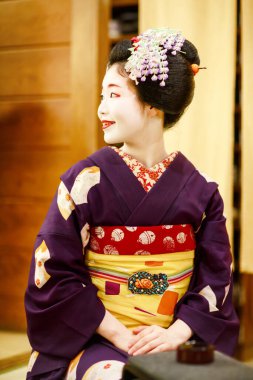 KYOTO, JAPAN - 18 May, 2015: Maiko apprentice showing Japanese traditional dance. Maiko is an apprentice geisha. Maikos performing songs, playing shamisen or instruments for visitors on ozashiki clipart