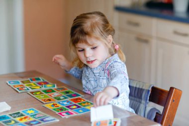 Heyecanlı, gülümseyen küçük kız iskambil oynuyor. Mutlu sağlıklı çocuk hafızasını eğitiyor, düşünüyor. Çocuk için evde yaratıcı bir eğlence ve eğitim. Evde aile aktivitesi