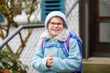Okula giderken ya da gelirken çok tatlı bir kızdı. İlkokula giderken gözlüklü sağlıklı ve mutlu bir çocuk. Okul çantalı gülümseyen çocuk şehir sokaklarında, açık havada. Okula geri dön.