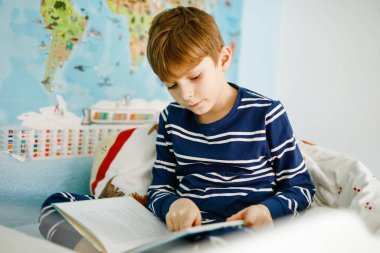 Sevimli sarışın küçük çocuk çocuk pijama onun yatak odasında kitap okuma. Yüksek sesle okuma, yatağında oturup sağlıklı çocuk heyecanlı. Temel, Aile, eğitim.