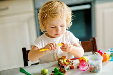 Evinde renkli kille sevimli, küçük bir kız. Sağlıklı bir bebek çocuk yuvasında ya da oyun okulunda hamur oynarken oyuncak yaratıyor. Kil kalıbı çıkaran küçük bir çocuk, yaratıcı aktivite.