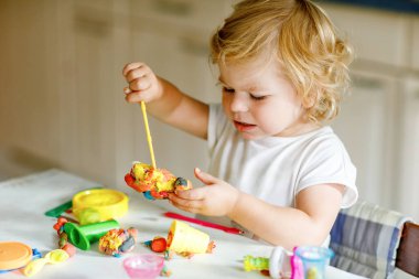 Evinde renkli kille sevimli, küçük bir kız. Sağlıklı bir bebek çocuk yuvasında ya da oyun okulunda hamur oynarken oyuncak yaratıyor. Kil kalıbı çıkaran küçük bir çocuk, yaratıcı aktivite.