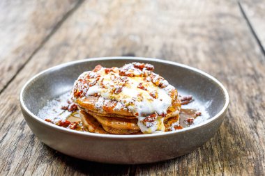 Fındıklı Amerikan krepleri, akçaağaç şurubu ve ahşap masada hindistan cevizi kreması. Kahvaltıda, kahvaltıda ya da açık kafede ya da restoranda öğle yemeğinde tatlı yiyecekler..