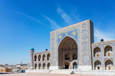 Semerkand, Özbekistan 'daki Registan Meydanı' nın bir parçası, parlak mavi gökyüzü altında karmaşık mozaik tasarımlar, kubbeler ve minareler içeren üç çarpıcı medresenin yer aldığı tarihi bir mimari grup..