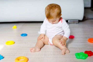 Bebek kız kreş eğitici oyuncaklar ile oynama. Mutlu sağlıklı çocuk evde renkli yumuşak oyuncaklar ile eğleniyor. Evlat plastik piramit inşa etmeye ve harflerle bloğu kullanma.