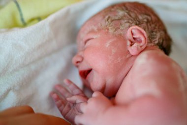Yeni doğan çocuk doğumdan saniyeler ve dakikalar sonra ağlıyor. Havlu üzerinde küçük şirin bir kız bebek. Yeni hayat, başlangıç, sağlık hizmetleri