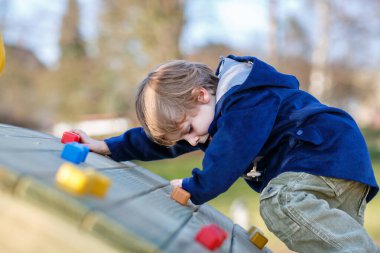 Çocuk, çocuk parkındaki küçük anaokulu çocuğu. Okul bahçesinde egzersiz yapan aktif bir çocuk. Çocuklar oynar ve tırmanır.