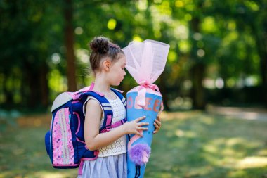 Sırt çantası, çantası ve büyük okul çantası olan mutlu küçük bir kız çocuğu ya da okulun ilk günü için Almanya 'da geleneksel Schultuete adı verilen bir koni. Yeni öğrenci, okula geri dön.