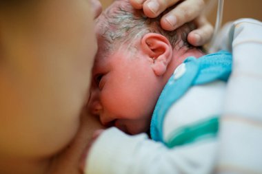 Yeni doğmuş bebek doğumdan sonra battaniyeye sarılmış. Anne ilk kez yeni doğmuş bir kızı arıyor. Yeni doğan çocuk doğumdan saniyeler ve dakikalar sonra. Mutlu anne ağlıyor..
