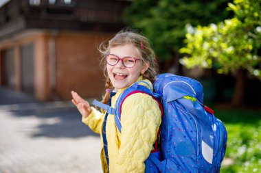 Gözlüklü, sırt çantalı, çantalı ve okulun ilk günü büyük çantalı mutlu bir kız çocuğu. Dışarıda sağlıklı, sevimli bir çocuk var. Okula geri dön..