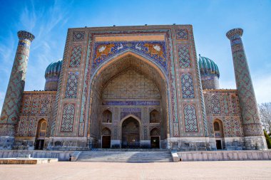 Semerkand, Özbekistan 'daki Registan Meydanı, parlak mavi gökyüzü altında karmaşık mozaik tasarımları, kubbeleri ve minareleri olan üç çarpıcı medresenin yer aldığı tarihi bir mimari topluluk..