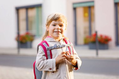 Anaokuluna giden tatlı küçük bir kız. Sağlıklı bir çocuk anaokuluna ve anaokuluna doğru yürüyor. Şehir caddesinde, açık havada sırt çantalı mutlu bir çocuk.