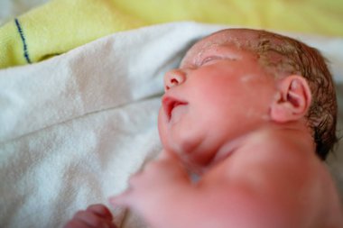 Yeni doğan çocuk doğumdan saniyeler ve dakikalar sonra ağlıyor. Havlu üzerinde küçük şirin bir kız bebek. Yeni hayat, başlangıç, sağlık hizmetleri