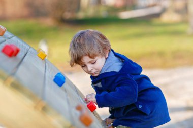 Çocuk, çocuk parkındaki küçük anaokulu çocuğu. Okul bahçesinde egzersiz yapan aktif bir çocuk. Çocuklar oynar ve tırmanır.