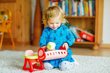 Oyuncak bebekle oynayan tatlı küçük kız. Mutlu sağlıklı bebek, rol yapma oyunuyla eğleniyor, evde ya da çocuk odasında annecilik oynuyor. Oyuncağı olan aktif bir çocuk