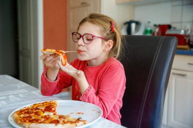 Küçük liseli kız bir dilim pizza yiyor. Mutlu Çocuk, domates ve peynirli pizza yiyor.
