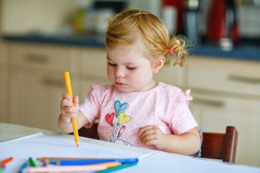 Kalemle resim yapmayı öğrenen sevimli bir bebek. Küçük çocuk renkli keçeli kalemlerle evde resim çiziyor. Evde ya da çocuk odasında renkler deneyen sağlıklı, mutlu bir kız.