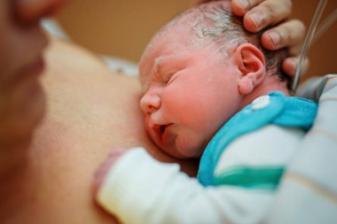 Yeni doğmuş bebek doğumdan sonra battaniyeye sarılmış. Anne ilk kez yeni doğmuş bir kızı arıyor. Yeni doğan çocuk doğumdan saniyeler ve dakikalar sonra. Mutlu anne ağlıyor..