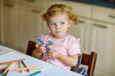 Kalemle resim yapmayı öğrenen sevimli bir bebek. Küçük çocuk renkli keçeli kalemlerle evde resim çiziyor. Evde ya da çocuk odasında renkler deneyen sağlıklı, mutlu bir kız.