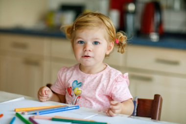 Kalemle resim yapmayı öğrenen sevimli bir bebek. Küçük çocuk renkli keçeli kalemlerle evde resim çiziyor. Evde ya da çocuk odasında renkler deneyen sağlıklı, mutlu bir kız.