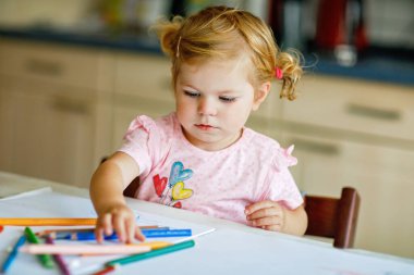 Kalemle resim yapmayı öğrenen sevimli bir bebek. Küçük çocuk renkli keçeli kalemlerle evde resim çiziyor. Evde ya da çocuk odasında renkler deneyen sağlıklı, mutlu bir kız.