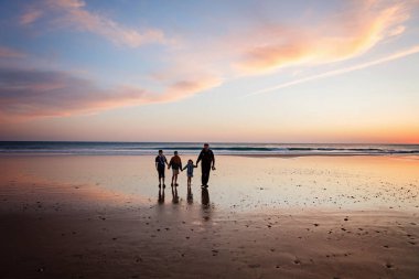 Gün batımında üç çocuk ve babanın resimli mutlu çocukları ve babaları sahilde. Mutlu bir aile, iki okul çocuğu ve küçük bir anaokulu kızı. Kardeşler birlikte eğleniyor. Bağlanma.