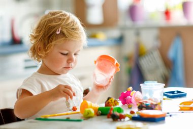 Evinde renkli kille sevimli, küçük bir kız. Sağlıklı bir bebek çocuk yuvasında ya da oyun okulunda hamur oynarken oyuncak yaratıyor. Kil kalıbı çıkaran küçük bir çocuk, yaratıcı aktivite.