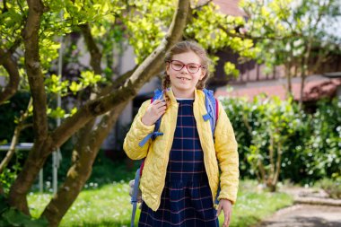 Gözlüklü, sırt çantalı, çantalı ve okulun ilk günü büyük çantalı mutlu bir kız çocuğu. Dışarıda sağlıklı, sevimli bir çocuk var. Okula geri dön..