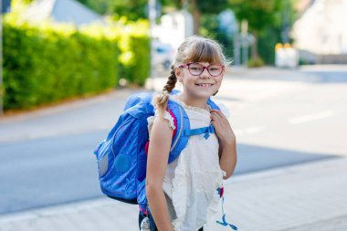 Gözlüklü şirin bir ilkokul öğrencisi sabah okula sırt çantasıyla gidiyor. Gerçek hayat, gerçek insanlar, günlük hayatta mutlu öğrenci.