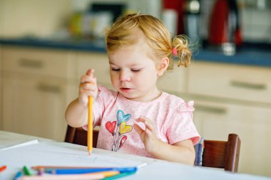 Kalemle resim yapmayı öğrenen sevimli bir bebek. Küçük çocuk renkli keçeli kalemlerle evde resim çiziyor. Evde ya da çocuk odasında renkler deneyen sağlıklı, mutlu bir kız.
