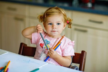 Kalemle resim yapmayı öğrenen sevimli bir bebek. Küçük çocuk renkli keçeli kalemlerle evde resim çiziyor. Evde ya da çocuk odasında renkler deneyen sağlıklı, mutlu bir kız.