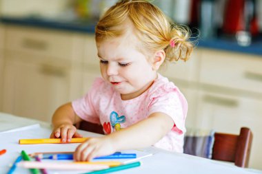 Kalemle resim yapmayı öğrenen sevimli bir bebek. Küçük çocuk renkli keçeli kalemlerle evde resim çiziyor. Evde ya da çocuk odasında renkler deneyen sağlıklı, mutlu bir kız.